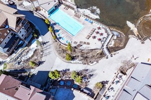 An aerial view of a resort with a swimming pool, lounge chairs, and a dock by the water. - On Main St. Hot Tubs, Easy Access to Peak 9. (Breckenridge)