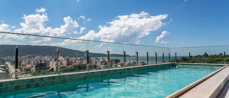 Una piscina techada, una piscina al aire libre, sombrillas