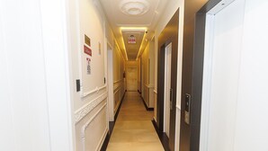 A hotel hallway with a long corridor, doors on both sides, and a sign indicating a room type. - Elegance Residence (Bombinhas)