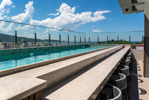 Una piscina techada, una piscina al aire libre, sombrillas