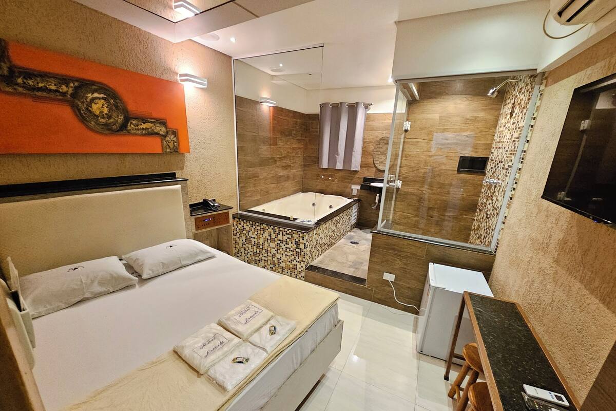 A modern hotel room with a bed, a desk, a shower, and a bathroom.