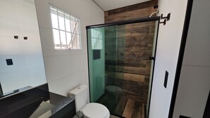 A modern bathroom with a glass shower enclosure, a toilet, and a vanity with a black countertop. - Hotel Estrela Carapicuiba (Carapicuiba)