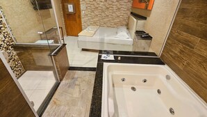 A modern bathroom with a large bathtub, a shower area, and a small bed. - Hotel Estrela Carapicuiba (Carapicuiba)