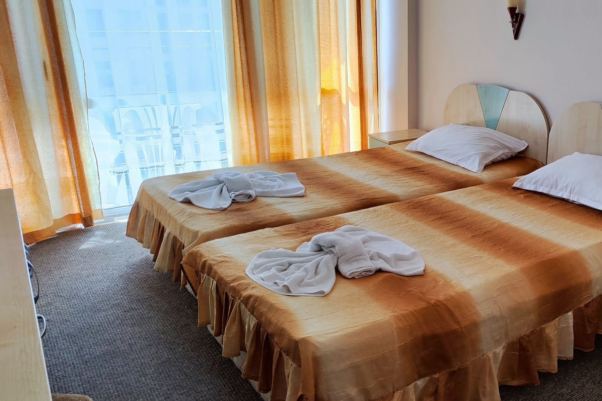 A hotel room with two beds, a chair, and a nightstand.