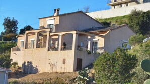 A two-story building with balconies, a flat roof, and a hillside location.