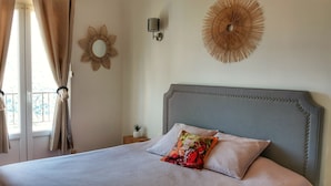 A bedroom with a bed, curtains, wall decor, and a small bedside table.