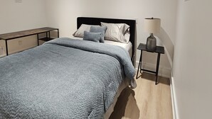 Un dormitori amb llit, taulella de nit i làmpada.