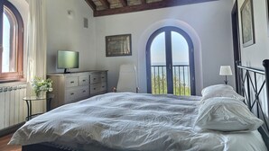 Une chambre à coucher avec un lit, une télévision, une commode et une fenêtre donnant sur un beau paysage.