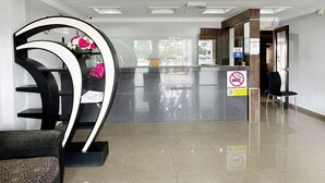 Un espace d’accueil moderne agrémenté d’une sculpture noire et blanche aux lignes courbes, d’un comptoir en verre et d’un panneau indiquant qu’il est interdit de fumer.
