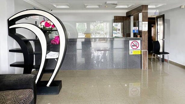 Un área de recepción moderna con una escultura curva blanco y negro, una barra de cristal y un cartel de prohibido fumar.