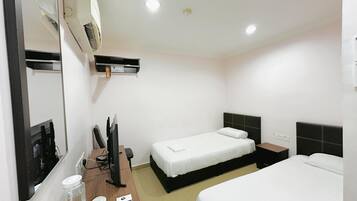 Quarto de hotel com duas camas, uma mesa de escritório com computador, um espelho e um ar condicionado fixado na parede.