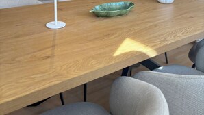 A modern dining area with a wooden table, white lamps, and a vase with flowers. - HyggeLiving | 94m² | view of Marktkirche | OSCAR (Goslar)