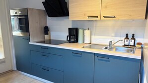 A modern kitchen with a built-in oven, a coffee maker, and a sink. - HyggeLiving | 94m² | view of Marktkirche | OSCAR (Goslar)