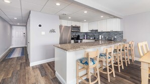Eine moderne Küche mit weißen Schränken, einem Edelstahl-Kühlschrank, einer Mikrowelle und einer Arbeitsplatte aus Granit.