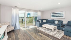 Ein modernes Wohnzimmer mit einer Couch, einem Couchtisch und einem Balkon mit Blick auf einen Wasserturm.