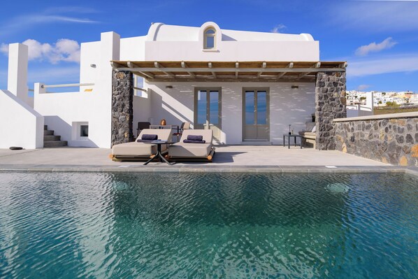 Relax by the serene pool surrounded by a stone wall and pergola, offering a tranquil space for unwinding.