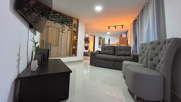 A modern living room with a sofa, a black side table, and a TV mounted on the wall. - 3-bedroom apartment in cool Envigado with WiFi (envigado)
