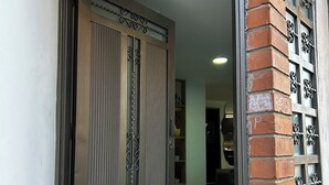 A doorway with a metal gate, a tiled floor, and a brick wall with decorative metal grilles. - 3-bedroom apartment in cool Envigado with WiFi (envigado)