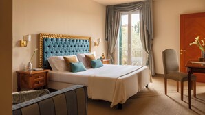 Une chambre d’hôtel avec un grand lit, une table de chevet, une chaise, un bureau et une vue sur l’extérieur.