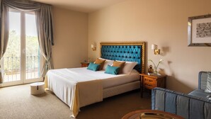 Une chambre d’hôtel comprenant un lit, une table de chevet, une chaise, une fenêtre avec des rideaux et un tableau accroché au mur.