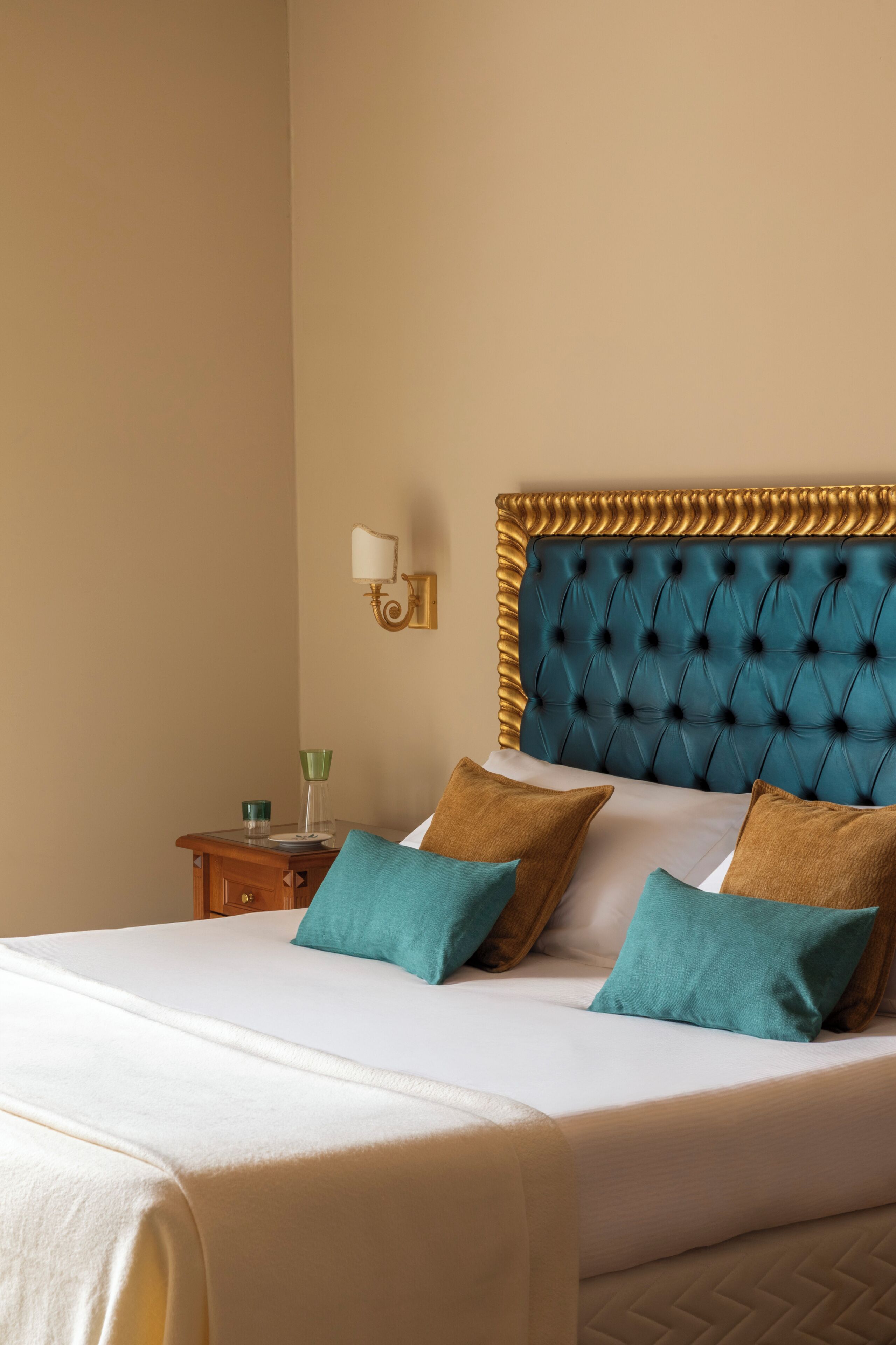 Hotelkamer met een groot bed, nachtkastje, wandlamp en decoratief wandpaneel.