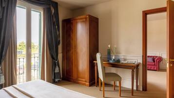 Una habitación de hotel con cama, escritorio, silla, armario y una puerta que da a otra habitación.