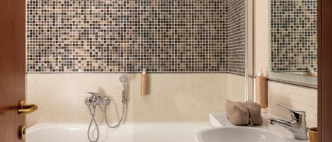Een badkamer met een bad, een wastafel en een douche.