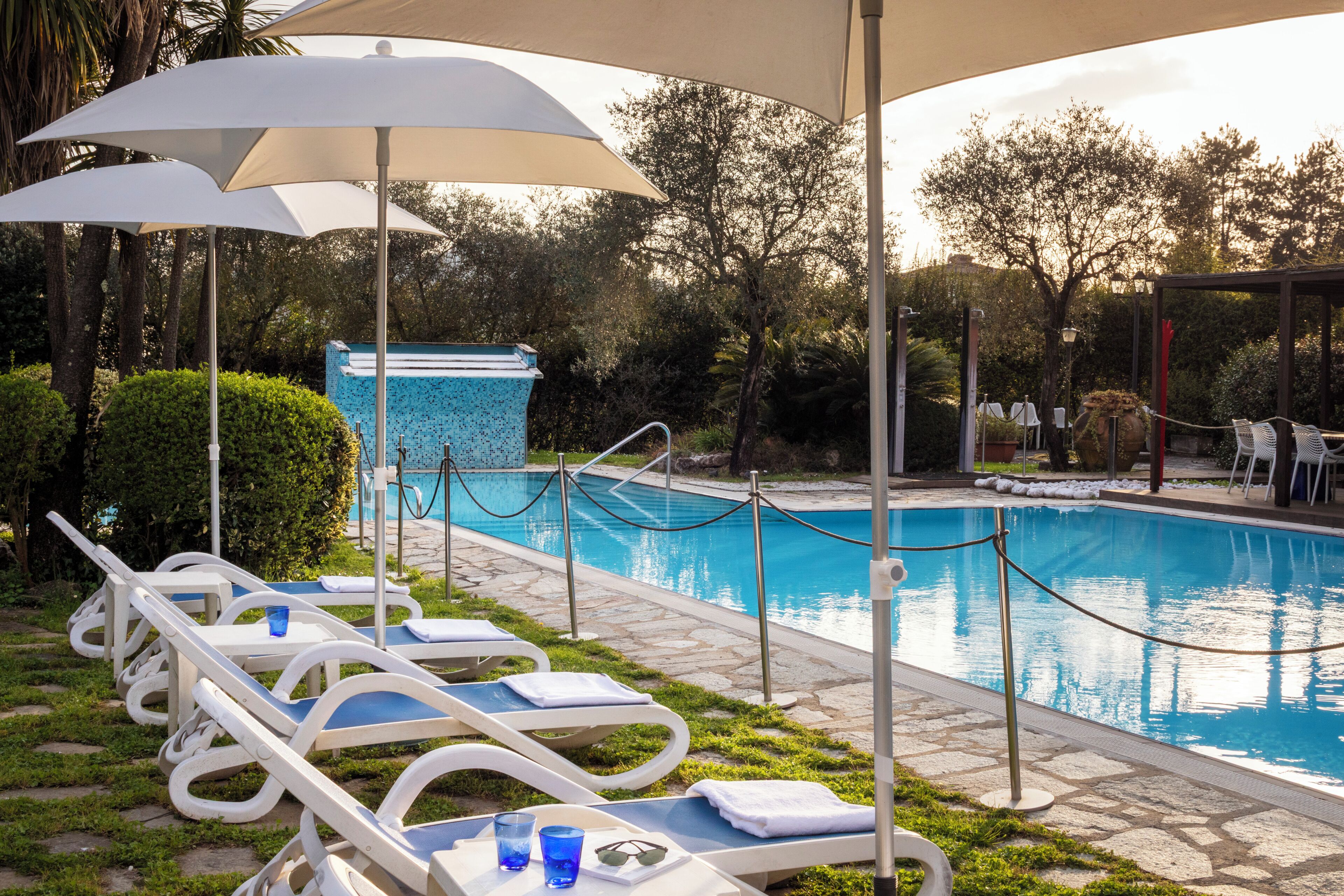 A poolside area with lounge chairs, umbrellas, and a pool.
