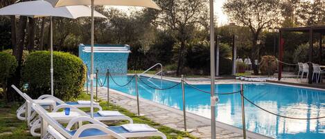A poolside area with lounge chairs, umbrellas, and a pool.