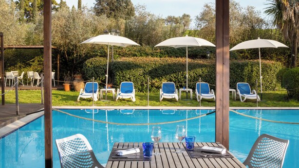 Un espace aménagé au bord de la piscine, avec des chaises longues, des parasols, une table, des verres et une serviette.