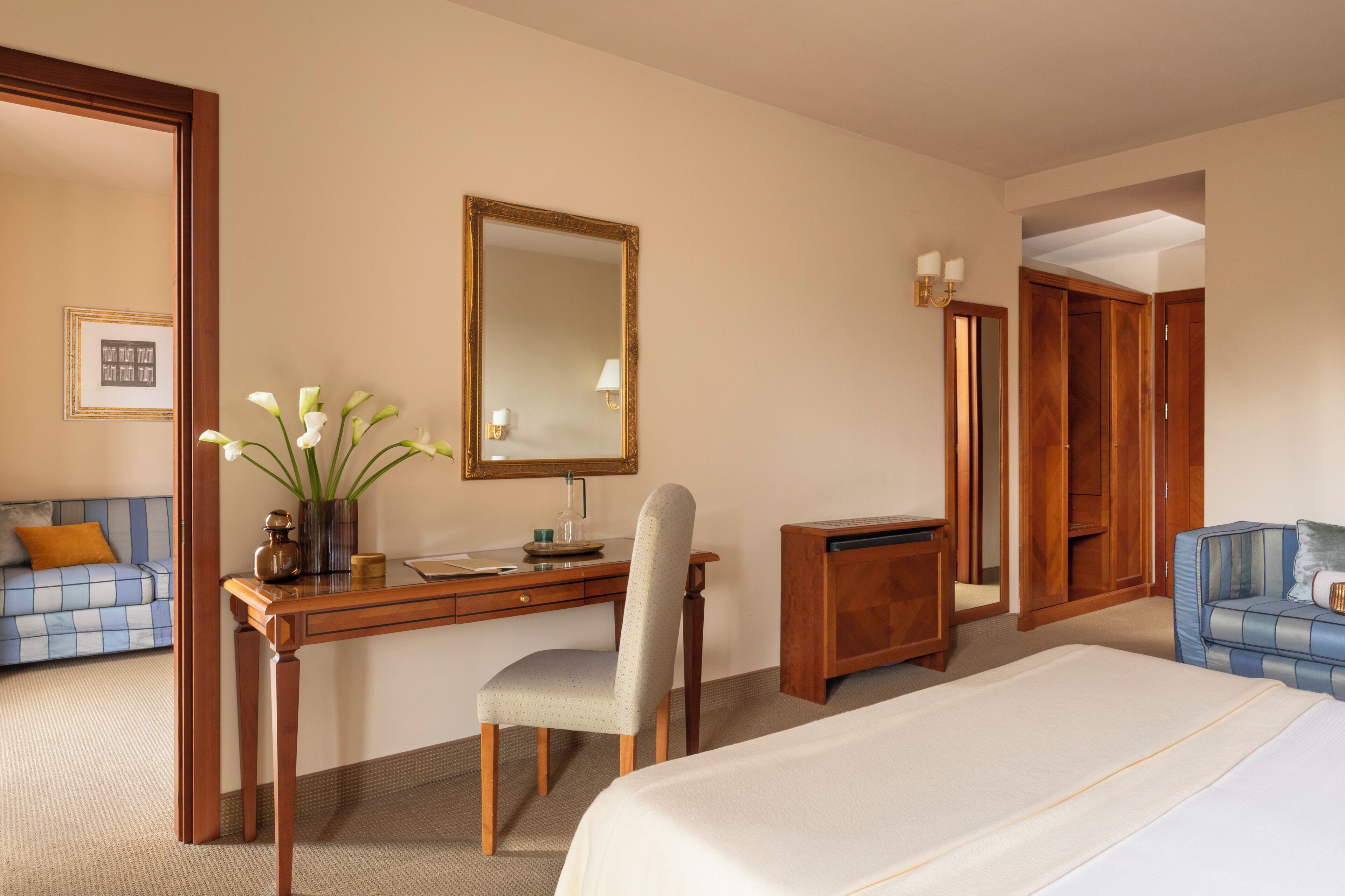 A hotel room with a bed, desk, chair, and a mirror.