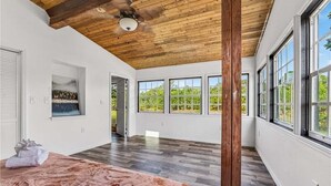 A spacious room with a wooden ceiling, large windows, and a view of greenery outside. - Relaxing Family Retreat In The Heart Of Sebastian 3 Bedroom Home (Sebastian)