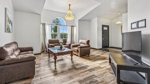 A spacious living room with a large window, a fireplace, and a ceiling light fixture. - Relaxing Family Retreat In The Heart Of Sebastian 3 Bedroom Home (Sebastian)