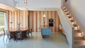 A modern kitchen with a central island, wooden panel walls, and a staircase with integrated lighting.