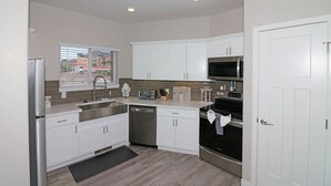 A modern kitchen with white cabinets, stainless steel appliances, and a window with a view of the outside. - Modern Ascend 2 Bedroom Townhouse (Grand Junction)