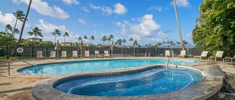 A swimming pool with lounge chairs and palm trees.