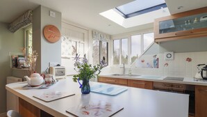 A modern kitchen with a central island, a skylight, and a view of the outdoors. - Bentley Rise (Lyme Regis)