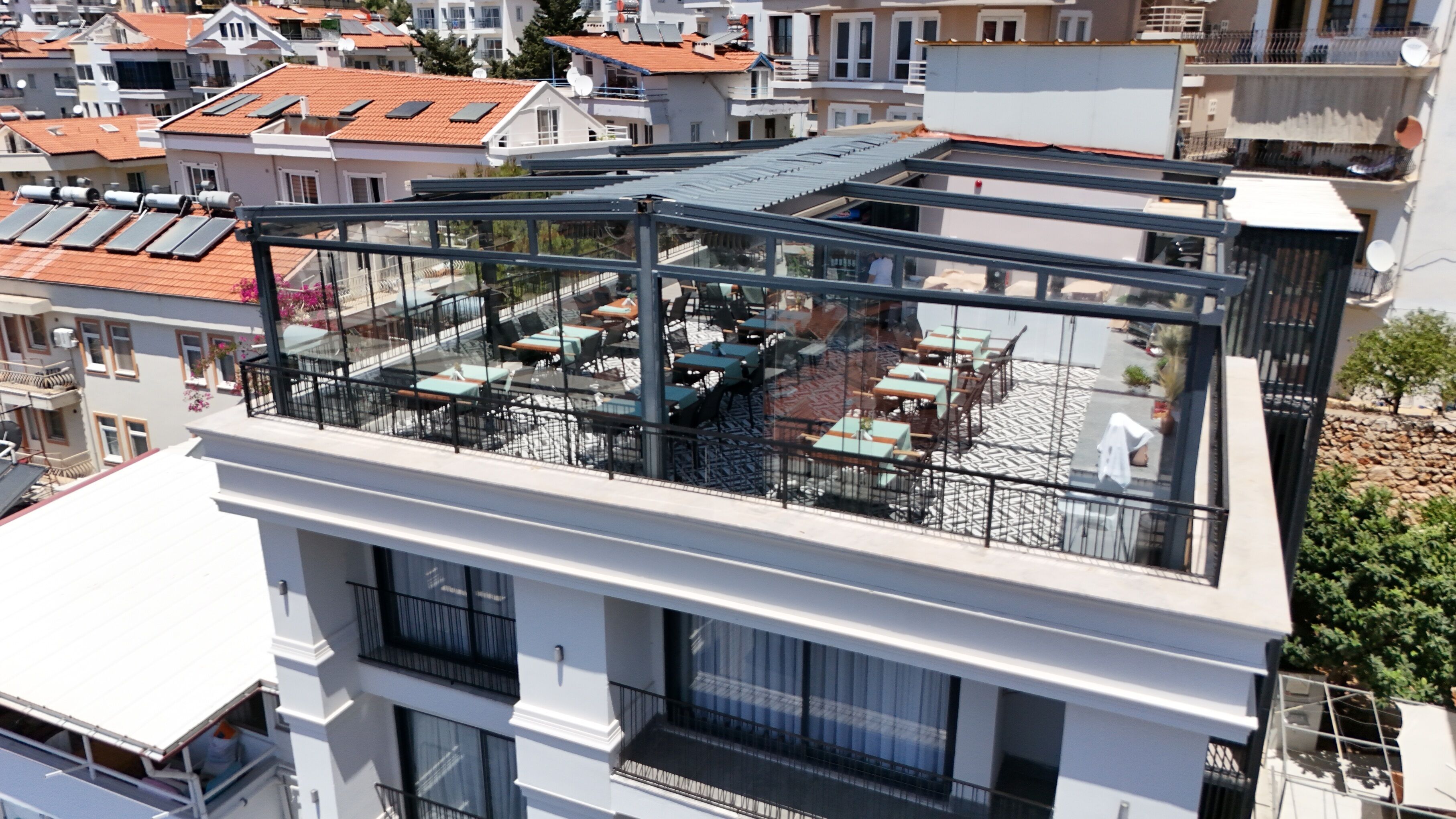 Un edificio moderno con terraza en la azotea, mobiliario exterior y cerramiento de vidrio.