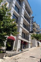 Un hotel de varios pisos con balcones, un bar y restaurante, y un toldo rojo.