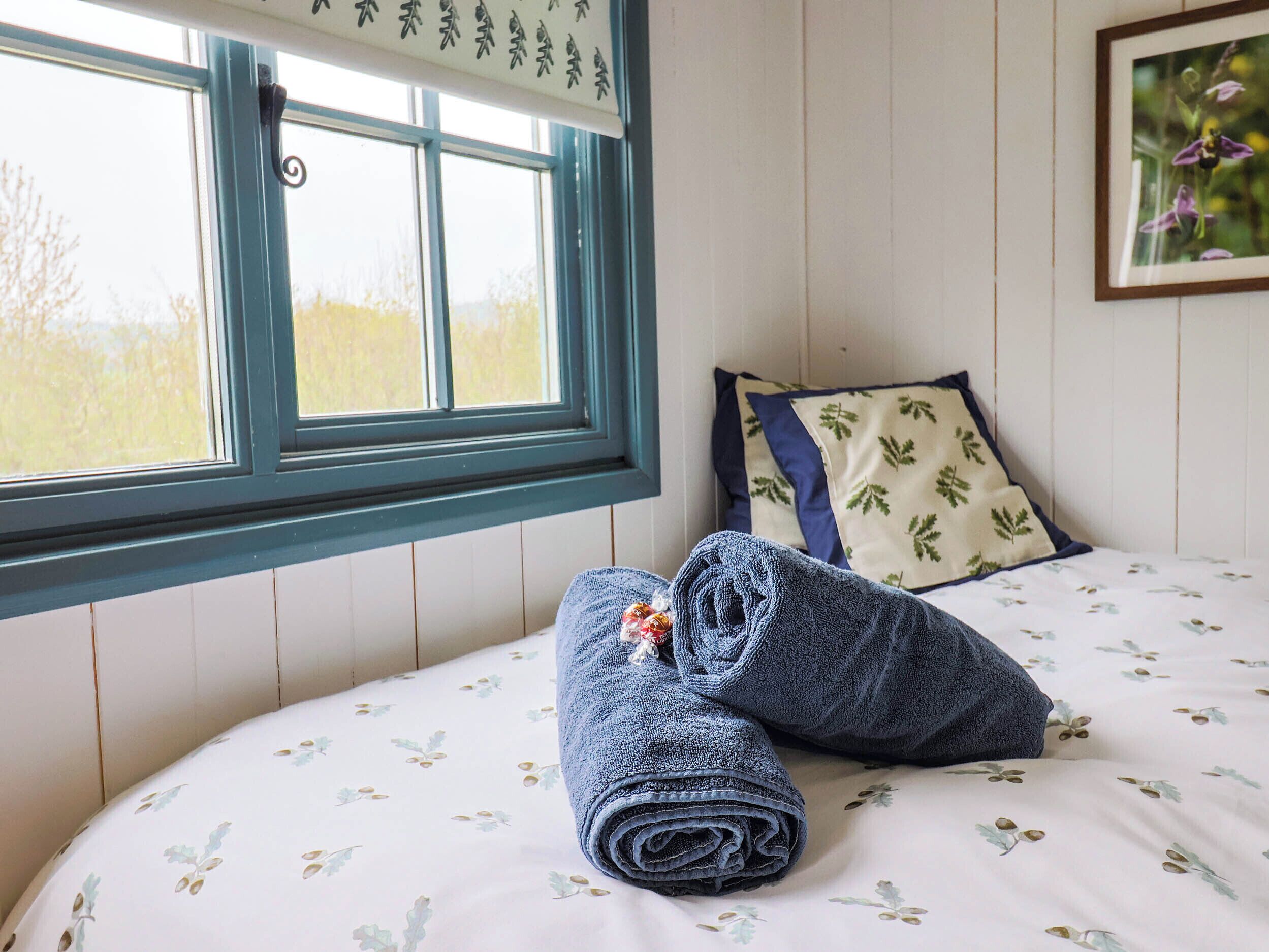 A bedroom with a bed, a window, and a pillow with a leaf pattern.