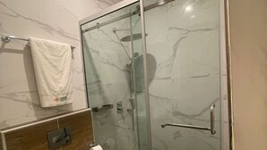 Et moderne badeværelse med bruseniche, toilet og håndklædestang.
