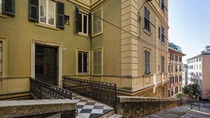 A building with a checkered stone staircase leading to a door with a metal railing. - The Designer s Flat by Wonderful Italy (Genoa)