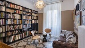 A cozy living room with a large bookshelf, a comfortable sofa, and a dining area. - The Designer s Flat by Wonderful Italy (Genoa)