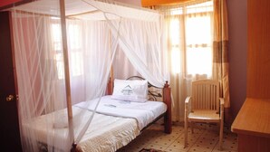 Une chambre avec un lit à baldaquin, une chaise et un bureau.
