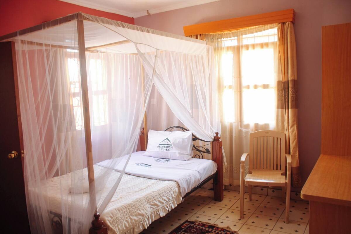A room with a four-poster bed, a chair, and a desk.
