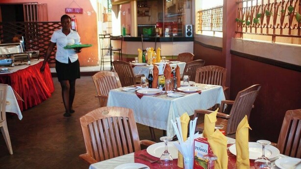 Un restaurant avec des tables dressées, un serveur portant un plateau et un menu affiché en évidence.