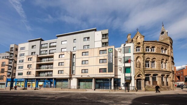 Un edificio moderno de varios pisos con espacios residenciales y comerciales, incluyendo un destacado edificio histórico con arquitectura ornamentada.