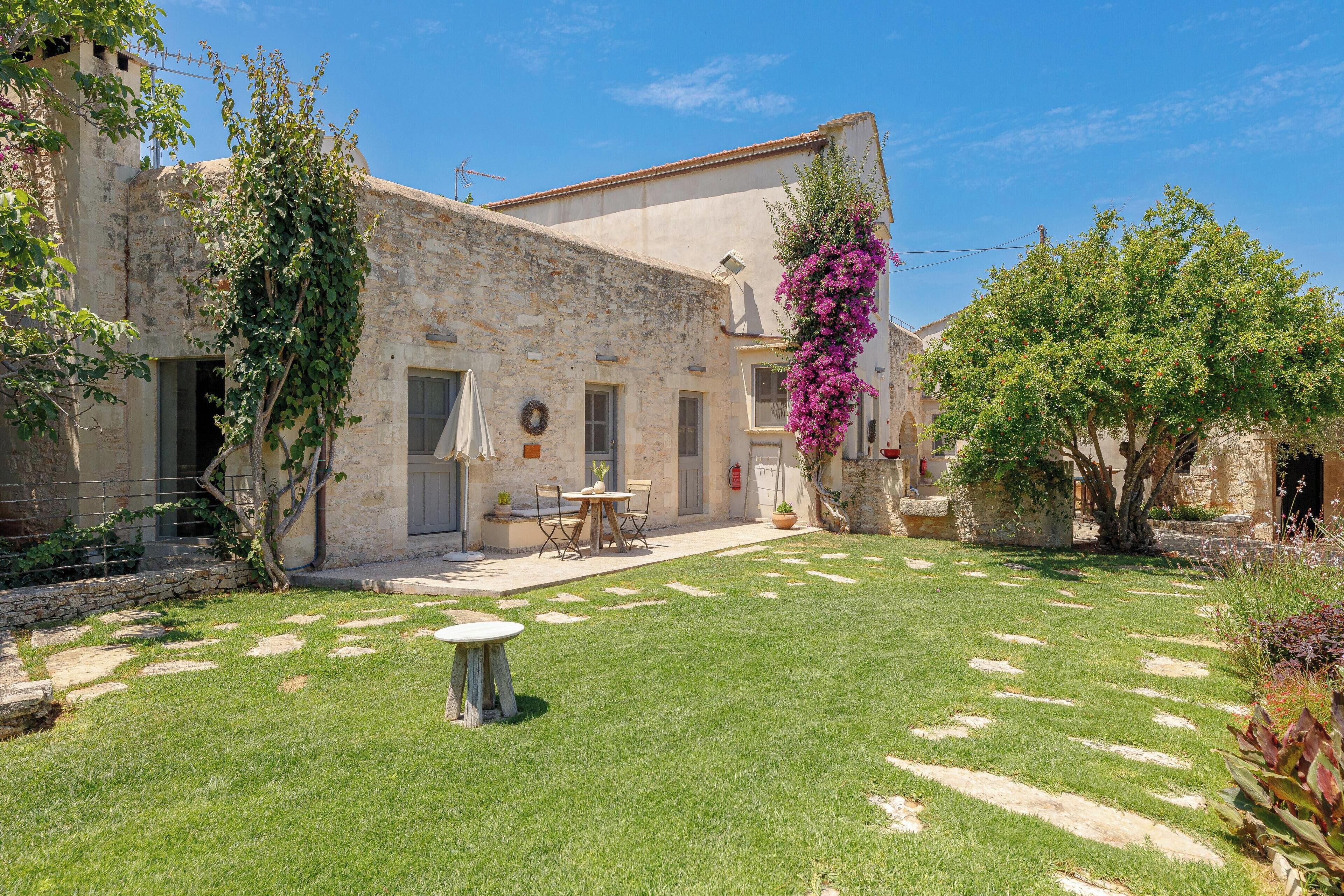 Un edificio in pietra con un piccolo patio, un tavolo e delle sedie.