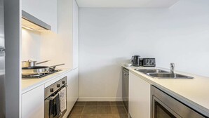 A compact kitchen with a stove, oven, sink, and a microwave. - Prime Location 1BD Apartment in Chatswood (Chatswood)