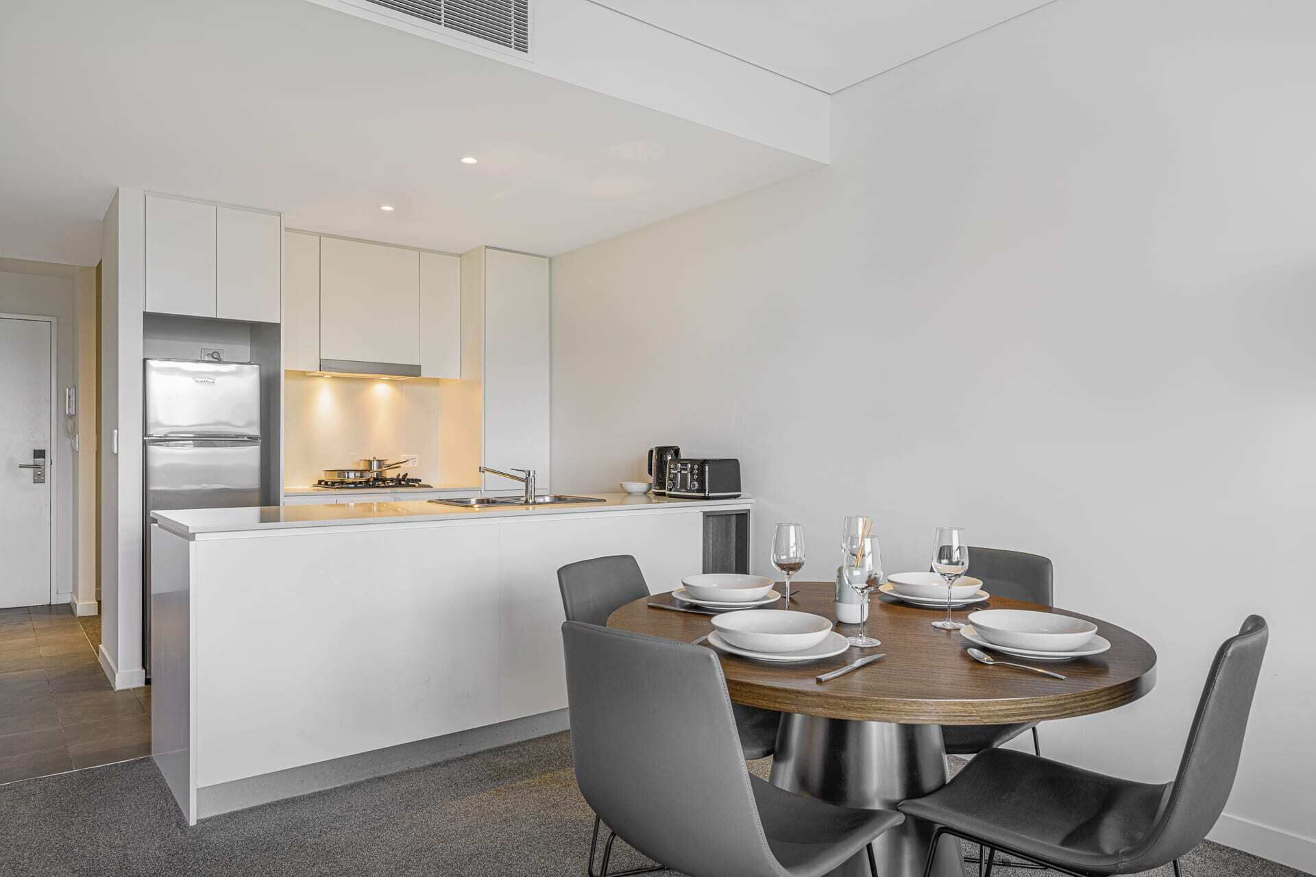 A modern kitchen with a central island, a dining table with chairs, and a small kitchenette area.